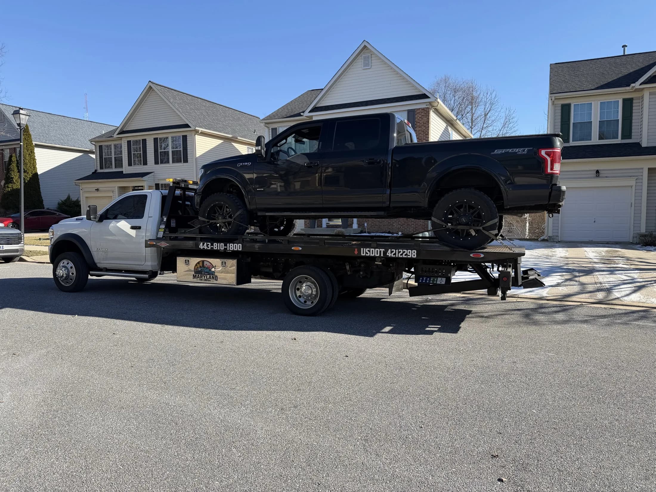Maryland Tow Company flatbed towing a pickup truck
